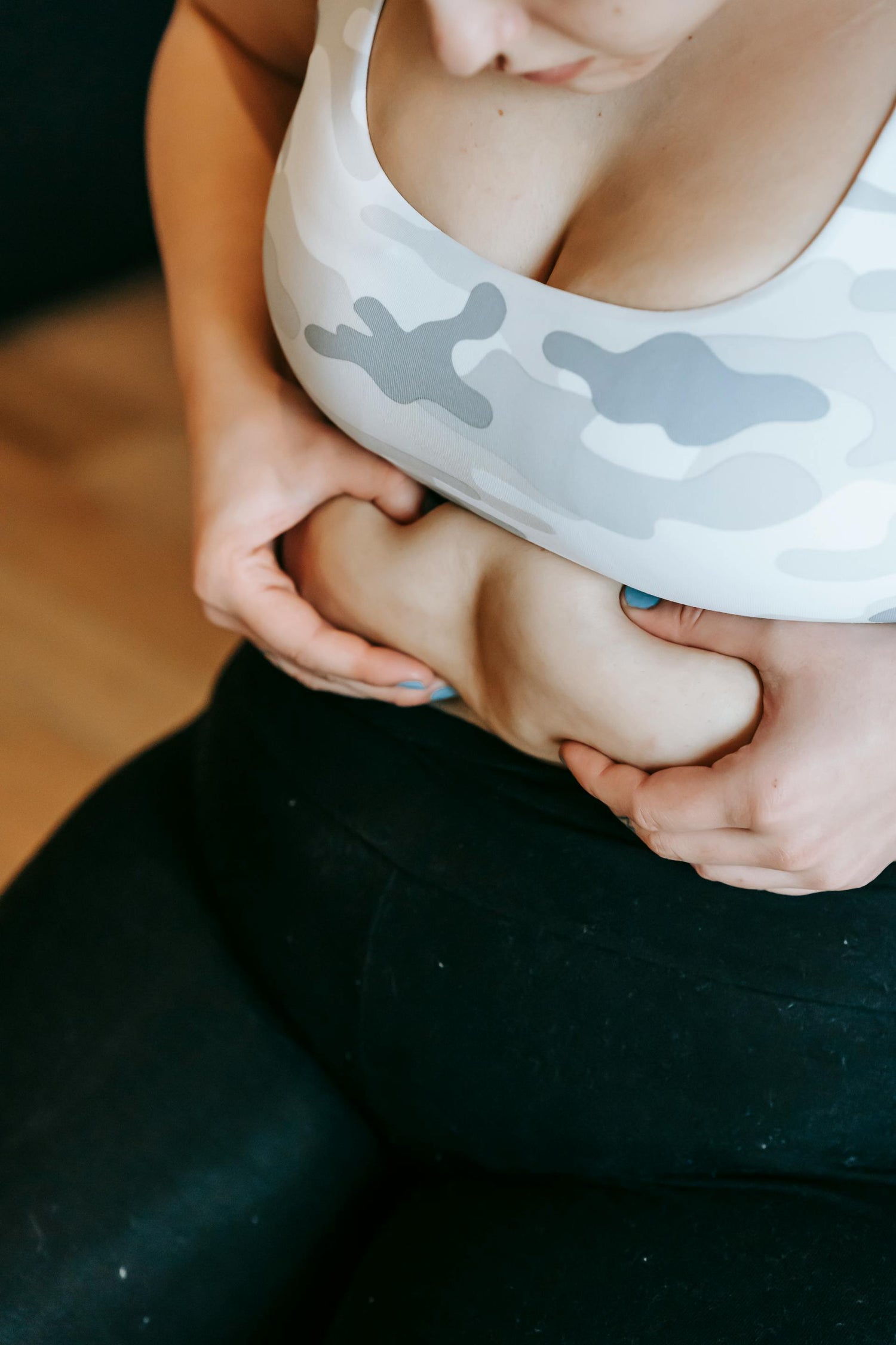 Femme pinçant son ventre pour mettre en évidence une prise de poids et la cellulite, illustrant les problématiques de minceur et de soin corporel