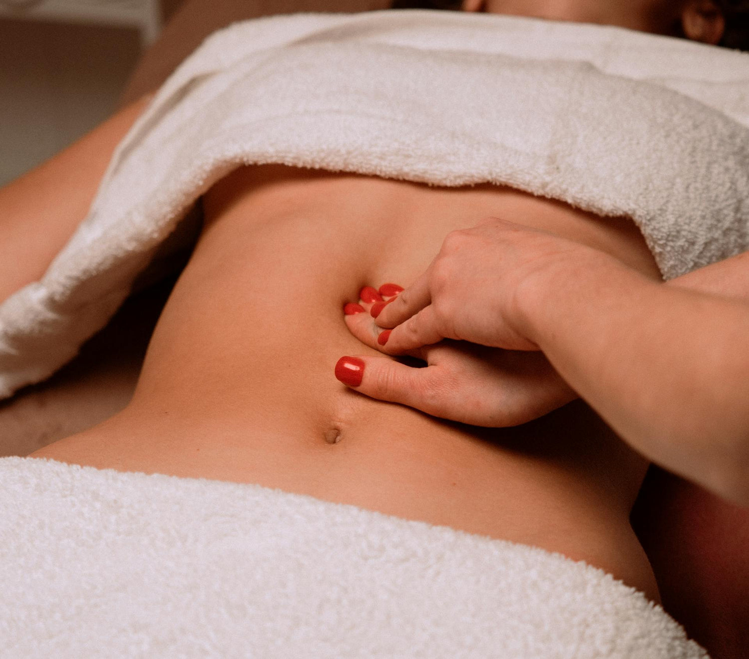 Une masseuse effectuant une pression sur le ventre d'une femme pour calmer des douleurs et apporter le bien-être